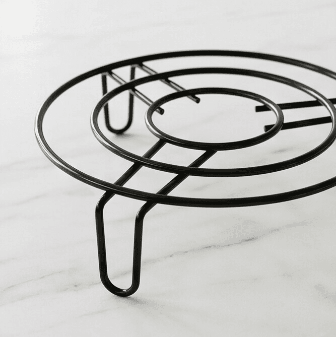 Durable round metal stand made of coated iron, designed to hold pots, kettles, or hot cookware, protecting countertops from heat damage.